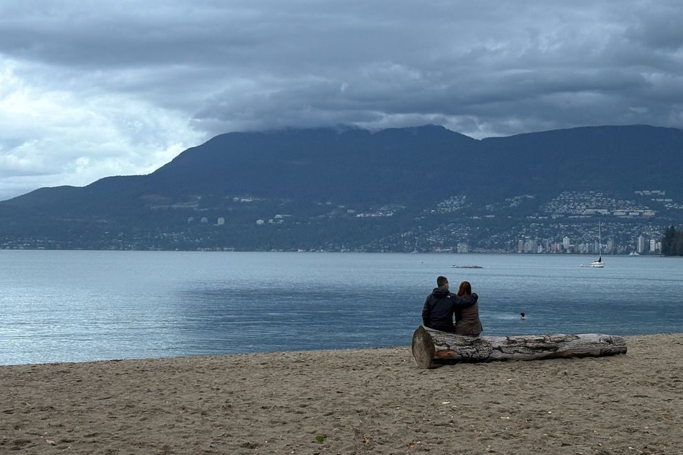 A couple sits at Kitsilano Beach on a cloudy autumn afternoon.(Bhagyashree Chatterjee/Daily Hive)